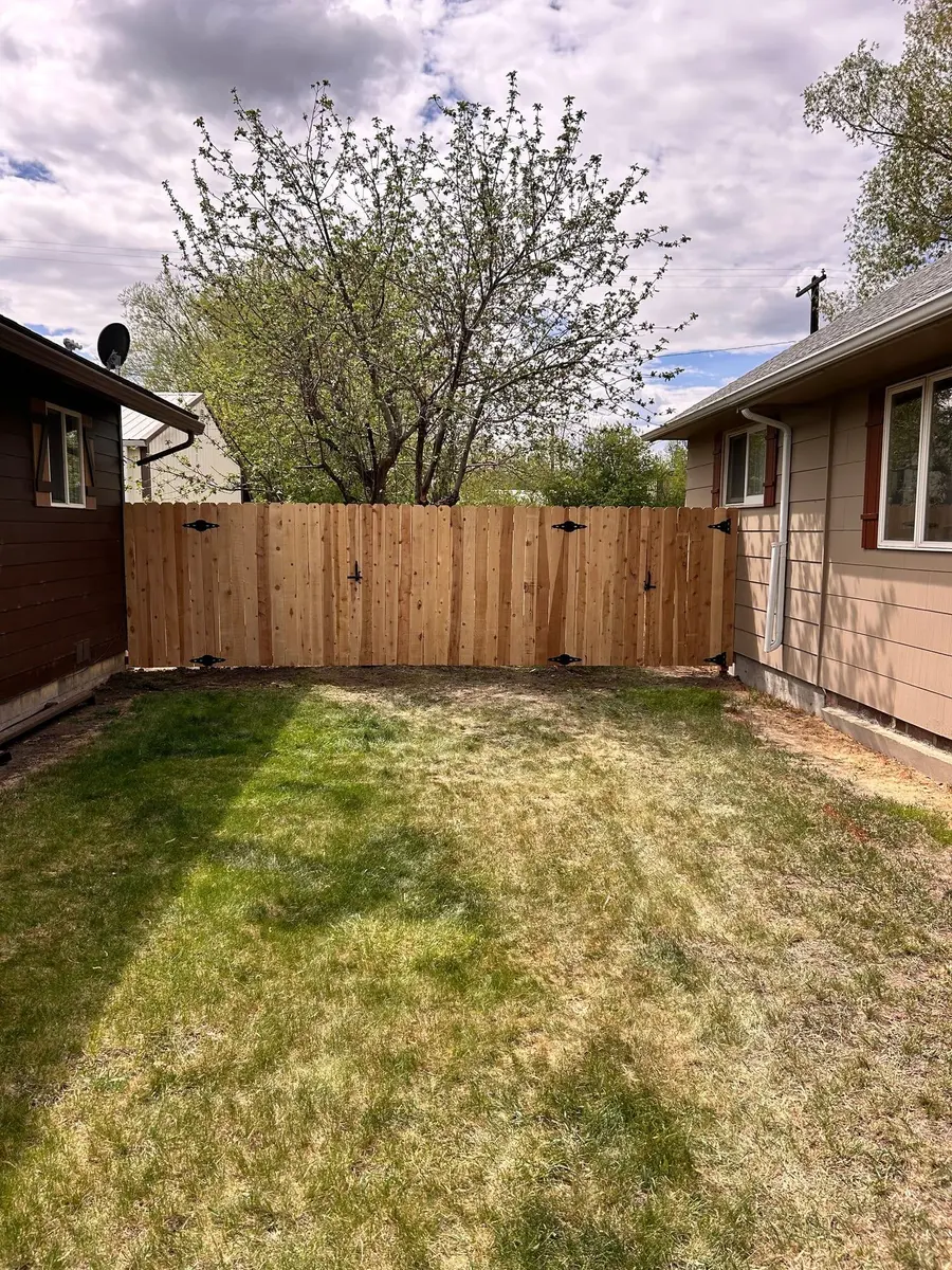 New cedar privacy fence and matching gates closing off a side yard between two houses