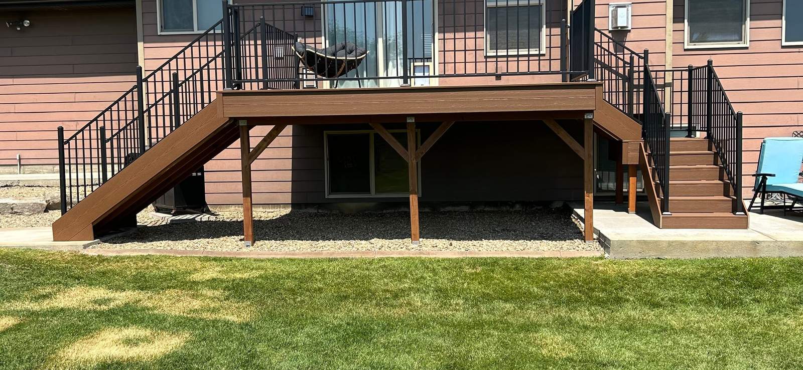 New elevated composite deck with black metal railing on the back of a Montana home
